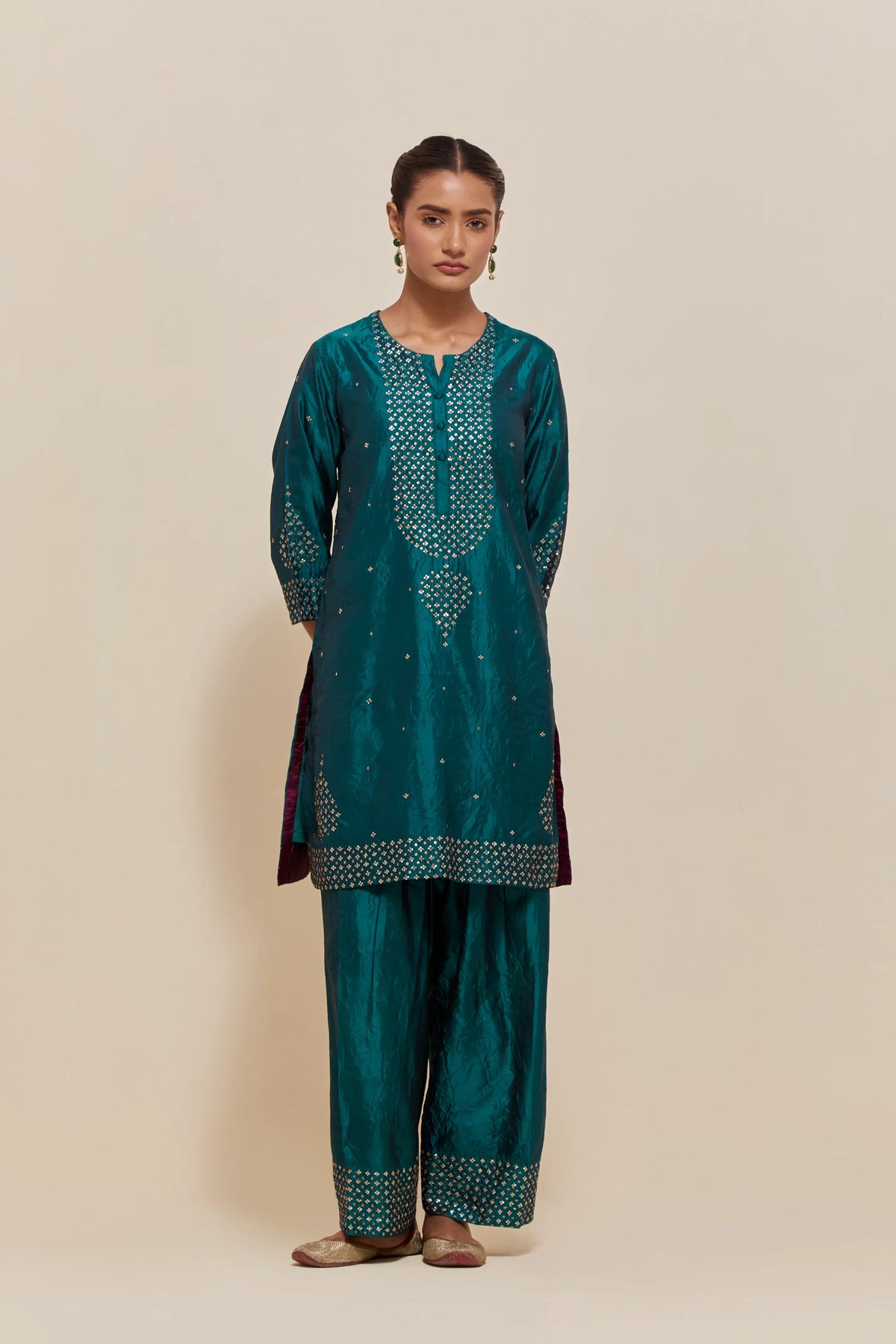Teal green silk straight short kurta set with hand-embroidered sequins at the neck, borders running along the hem and sleeve edges, and scattered gold sequins embellishments all-over.