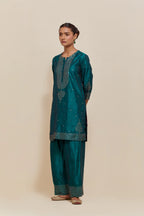 Teal green silk straight short kurta set with hand-embroidered sequins at the neck, borders running along the hem and sleeve edges, and scattered gold sequins embellishments all-over.