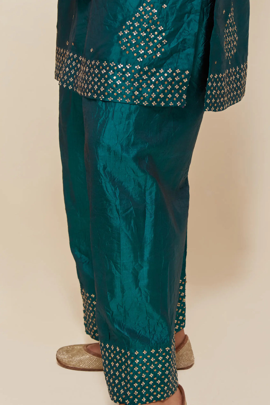 Teal green silk straight short kurta set with hand-embroidered sequins at the neck, borders running along the hem and sleeve edges, and scattered gold sequins embellishments all-over.