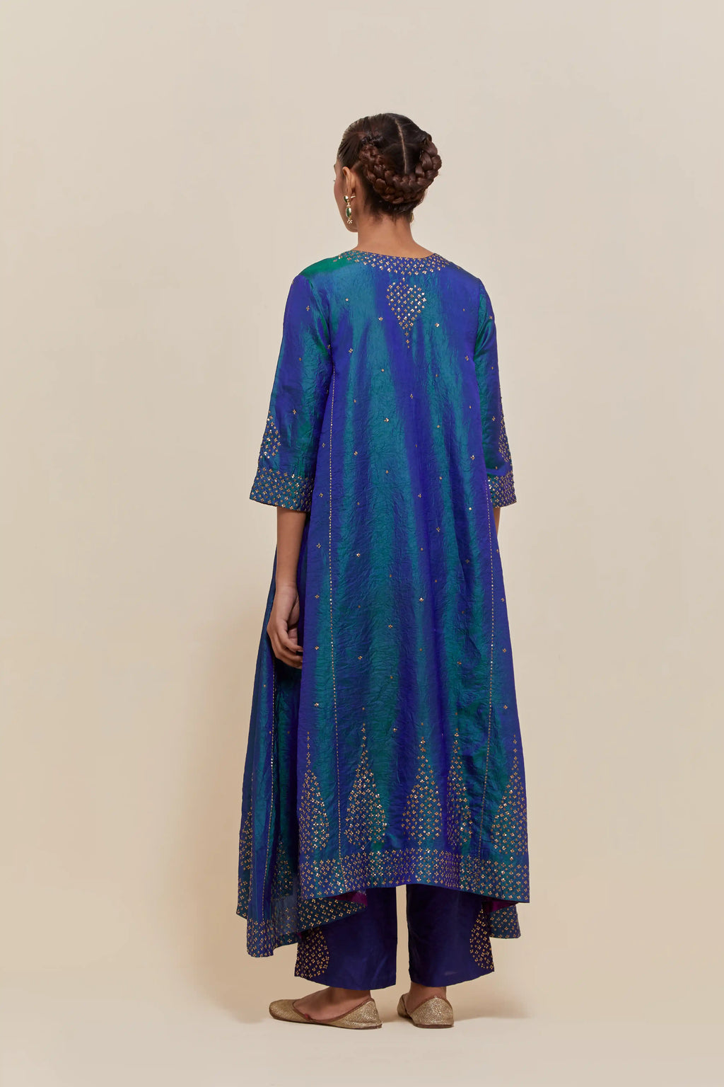 Teal blue silk kurta set with asymmetric hem and hand-embroidered leaf motifs with delicate sequins work at the neck, sleeves, and hem, with sequins border running along the edges.