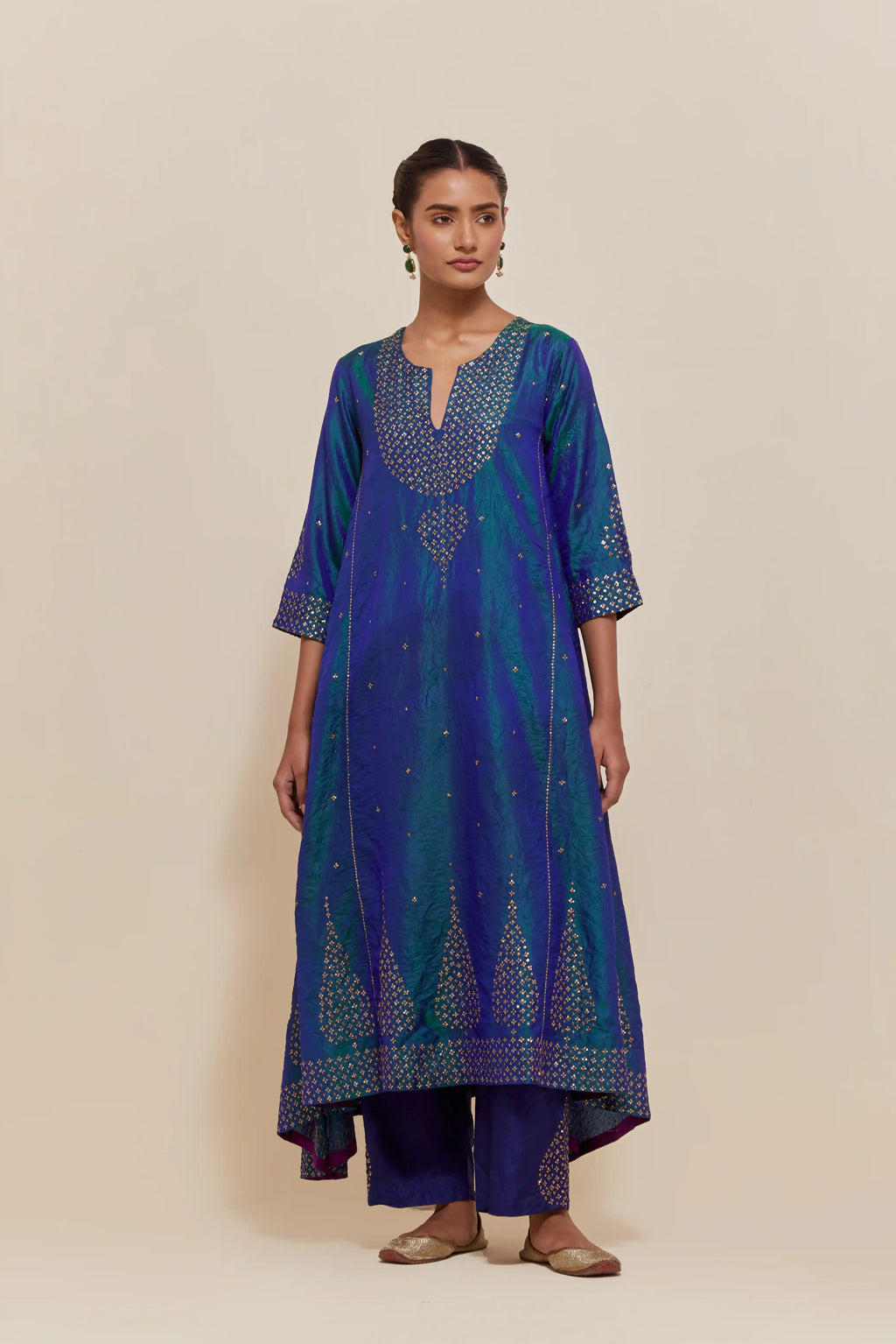 Teal blue silk kurta set with asymmetric hem and hand-embroidered leaf motifs with delicate sequins work at the neck, sleeves, and hem, with sequins border running along the edges.