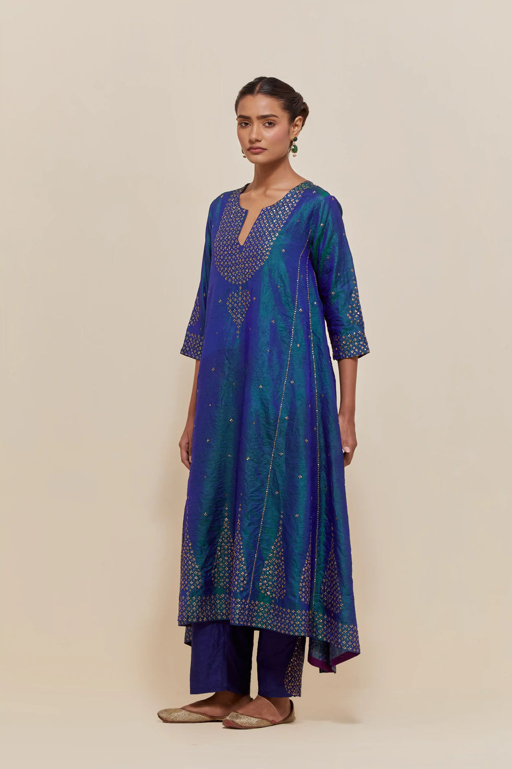 Teal blue silk kurta set with asymmetric hem and hand-embroidered leaf motifs with delicate sequins work at the neck, sleeves, and hem, with sequins border running along the edges.