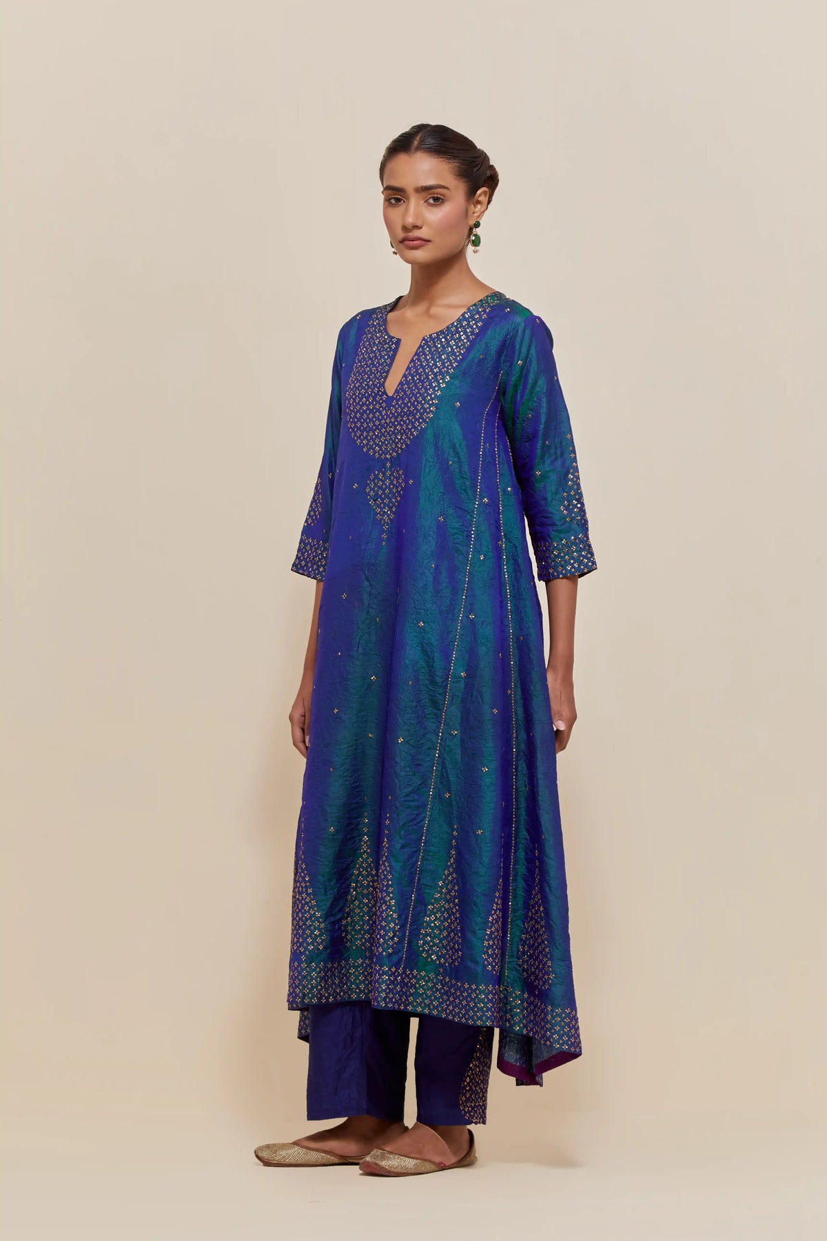 Teal blue silk kurta set with asymmetric hem and hand-embroidered leaf motifs with delicate sequins work at the neck, sleeves, and hem, with sequins border running along the edges.