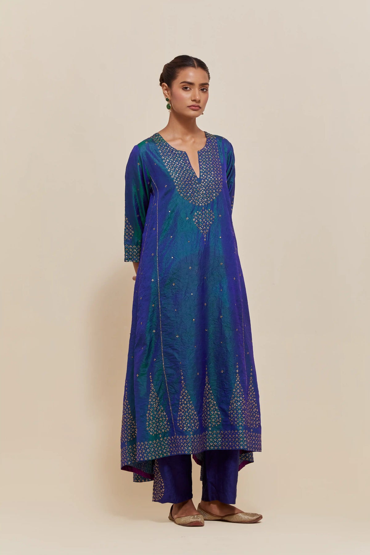Teal blue silk kurta set with asymmetric hem and hand-embroidered leaf motifs with delicate sequins work at the neck, sleeves, and hem, with sequins border running along the edges.