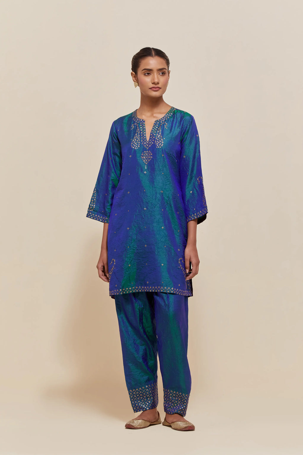 Teal blue silk straight short kurta set with hand-embroidered paisley motifs with delicate sequins work at neck, hem, and sleeves, with narrow borders along the edges.