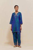Teal blue silk straight short kurta set with hand-embroidered paisley motifs with delicate sequins work at neck, hem, and sleeves, with narrow borders along the edges.
