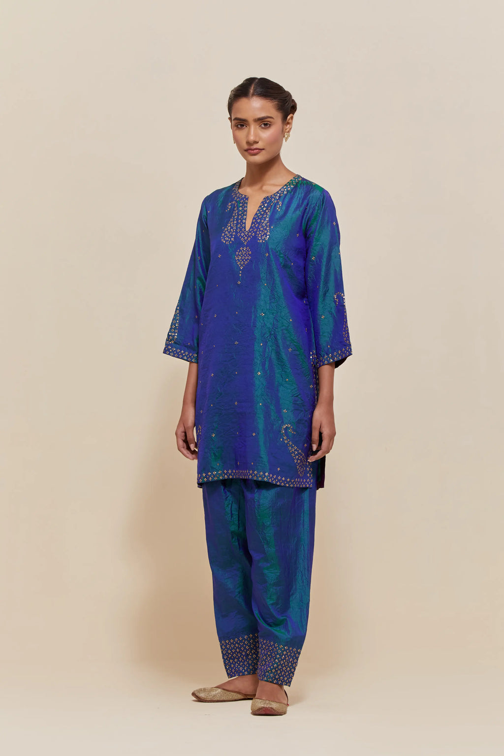 Teal blue silk straight short kurta set with hand-embroidered paisley motifs with delicate sequins work at neck, hem, and sleeves, with narrow borders along the edges.