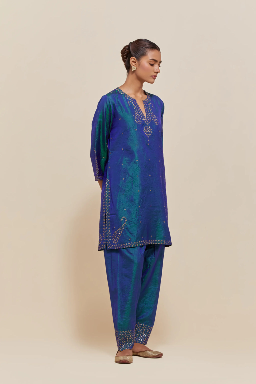 Teal blue silk straight short kurta set with hand-embroidered paisley motifs with delicate sequins work at neck, hem, and sleeves, with narrow borders along the edges.