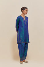 Teal blue silk straight short kurta set with hand-embroidered paisley motifs with delicate sequins work at neck, hem, and sleeves, with narrow borders along the edges.