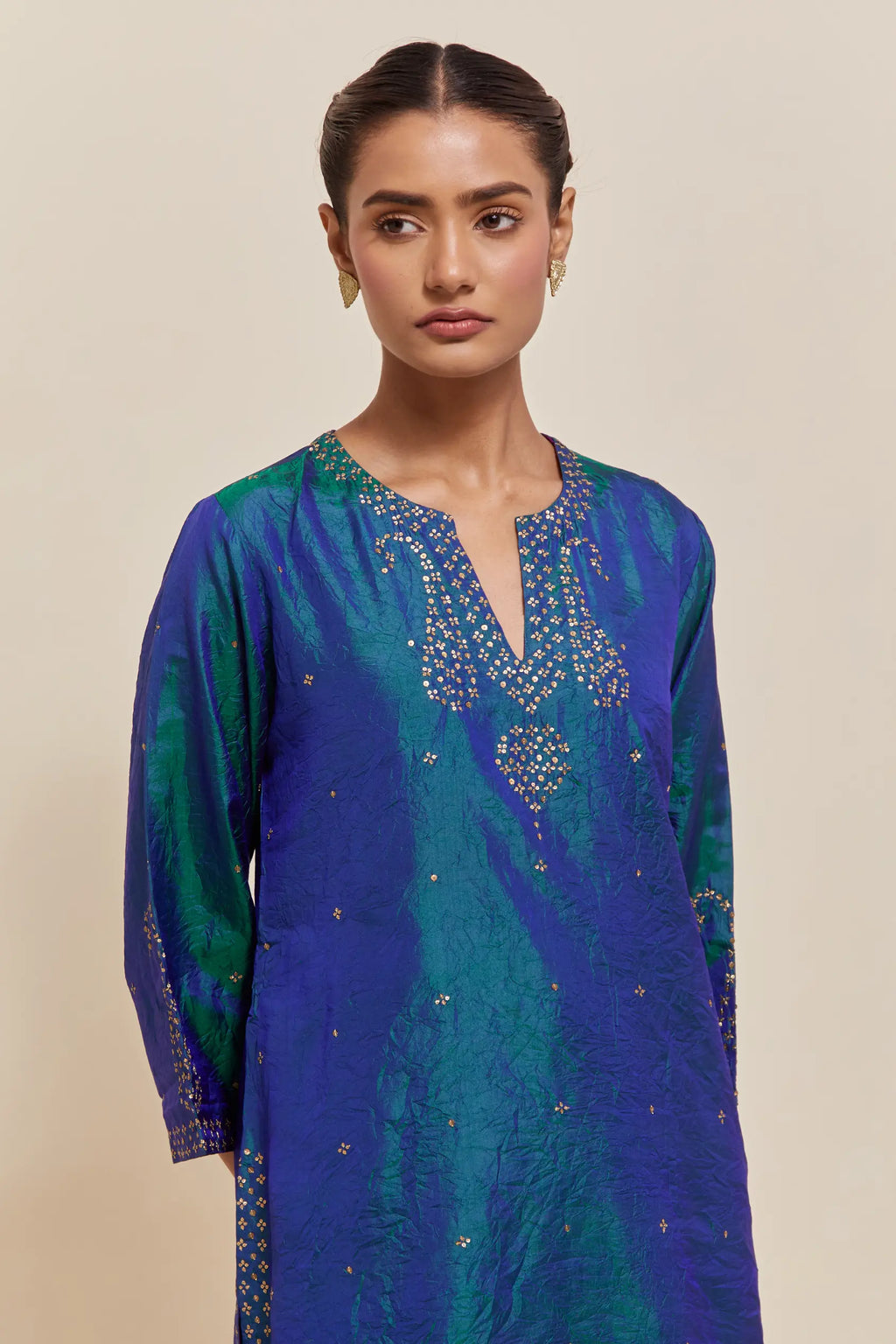 Teal blue silk straight short kurta set with hand-embroidered paisley motifs with delicate sequins work at neck, hem, and sleeves, with narrow borders along the edges.