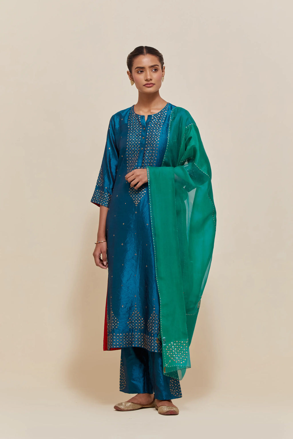Green silk dupatta with silk organza at the sides, highlighted with hand-embroidered gold sequins work.