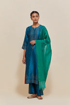 Teal silk straight kurta set with hand-embroidered sequins at the neck, borders running along the hem and sleeve edges, and scattered gold sequins embellishments all-over.