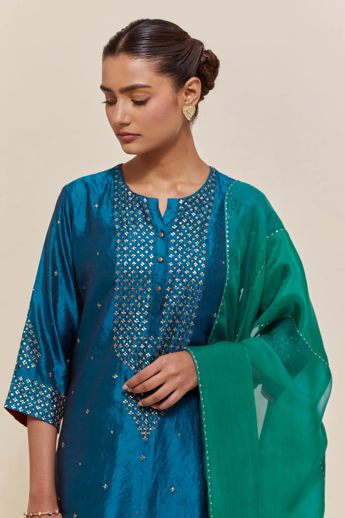 Green silk dupatta with silk organza at the sides, highlighted with hand-embroidered gold sequins work.