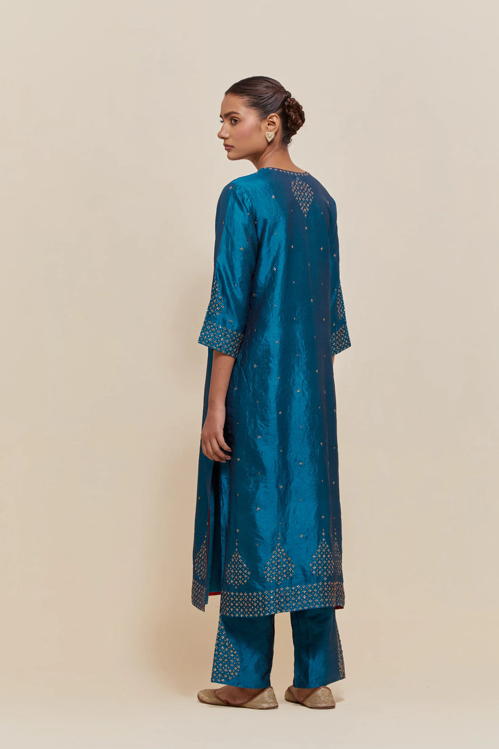 Teal silk straight kurta set with hand-embroidered sequins at the neck, borders running along the hem and sleeve edges, and scattered gold sequins embellishments all-over.
