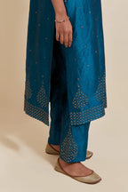 Teal silk straight kurta set with hand-embroidered sequins at the neck, borders running along the hem and sleeve edges, and scattered gold sequins embellishments all-over.