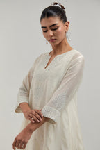 Off white silk Chanderi short kalidar kurta set, with hand embroidered mirror at neck, hem and sleeve edges, highlighted with scattered silver sequins and mirror embellishments all-over.