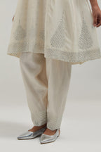 Off white silk Chanderi short kalidar kurta set, with hand embroidered mirror at neck, hem and sleeve edges, highlighted with scattered silver sequins and mirror embellishments all-over.