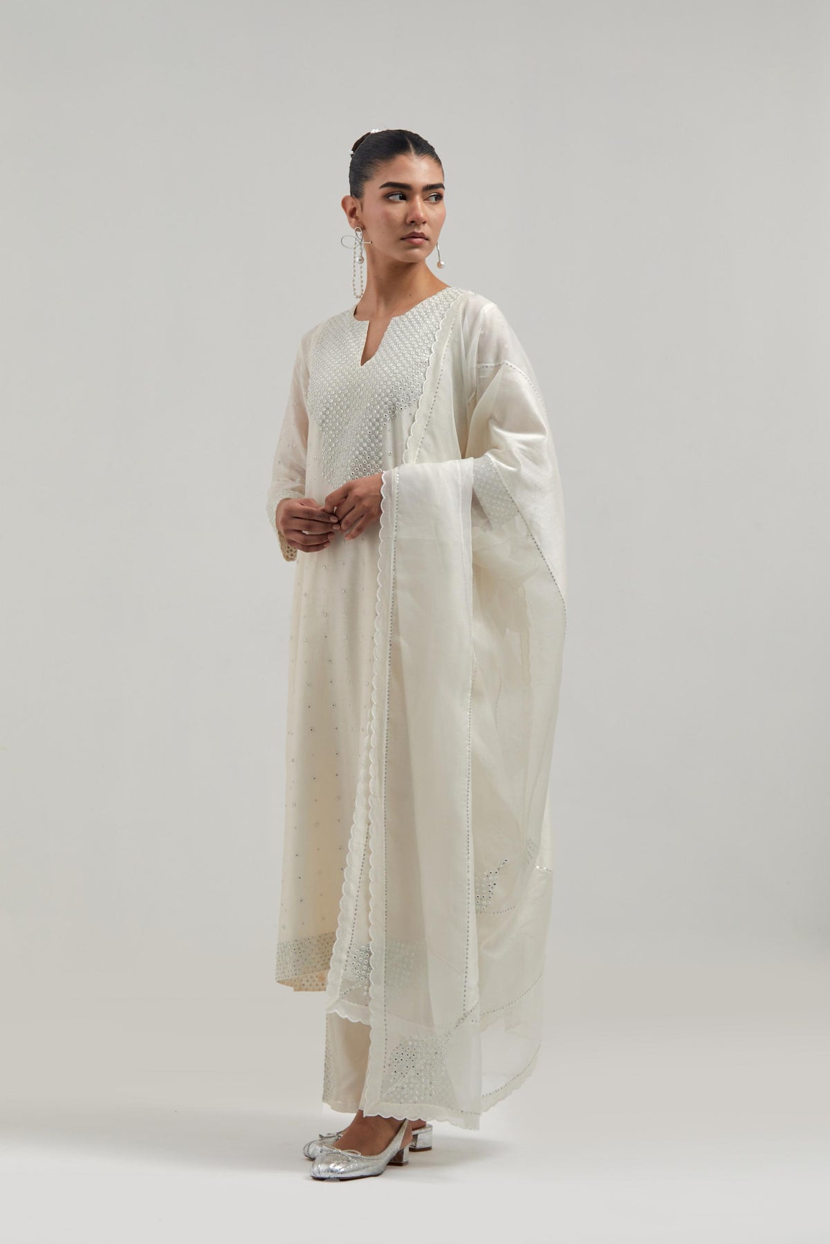 Off white silk Chanderi dupatta with silk organza at the sides, finished with delicate scalloped edges, highlighted by hand-embroidered mirror & sequins work.