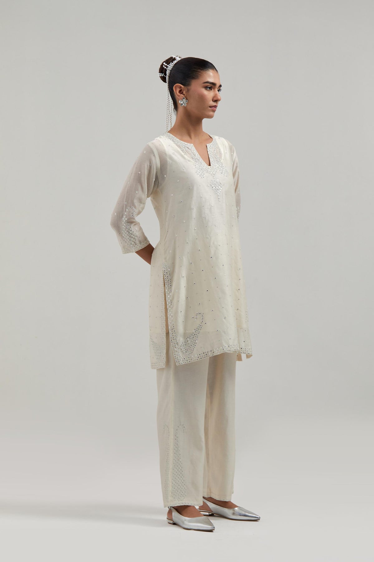 Off white silk Chanderi straight short kurta set with hand-embroidered paisley motifs with delicate mirror and sequins work at neck, hem, and sleeves, with narrow borders along the edges.