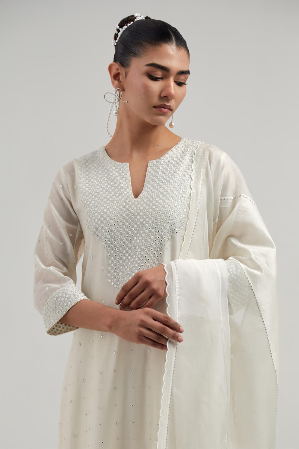 Off white silk Chanderi dupatta with silk organza at the sides, finished with delicate scalloped edges, highlighted by hand-embroidered mirror & sequins work.