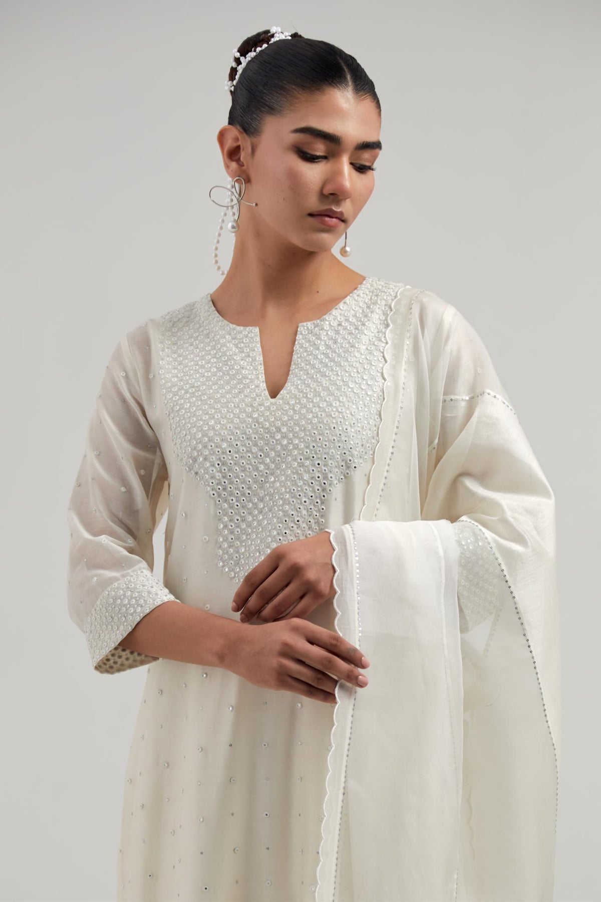 Off white silk Chanderi dupatta with silk organza at the sides, finished with delicate scalloped edges, highlighted by hand-embroidered mirror & sequins work.