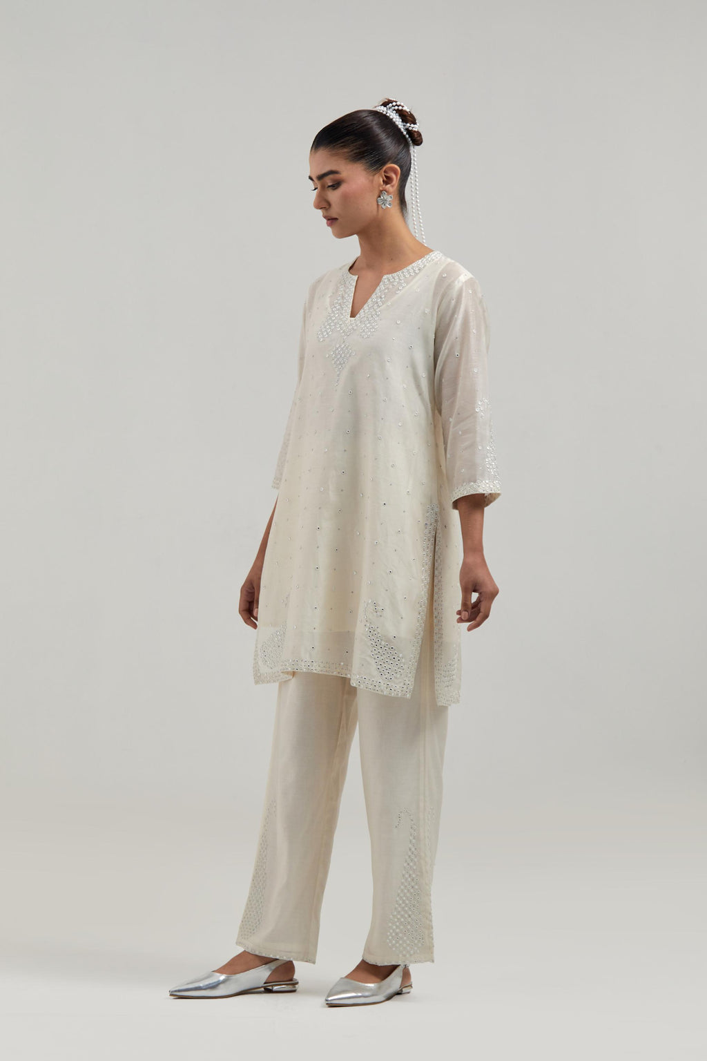 Off white silk Chanderi straight short kurta set with hand-embroidered paisley motifs with delicate mirror and sequins work at neck, hem, and sleeves, with narrow borders along the edges.