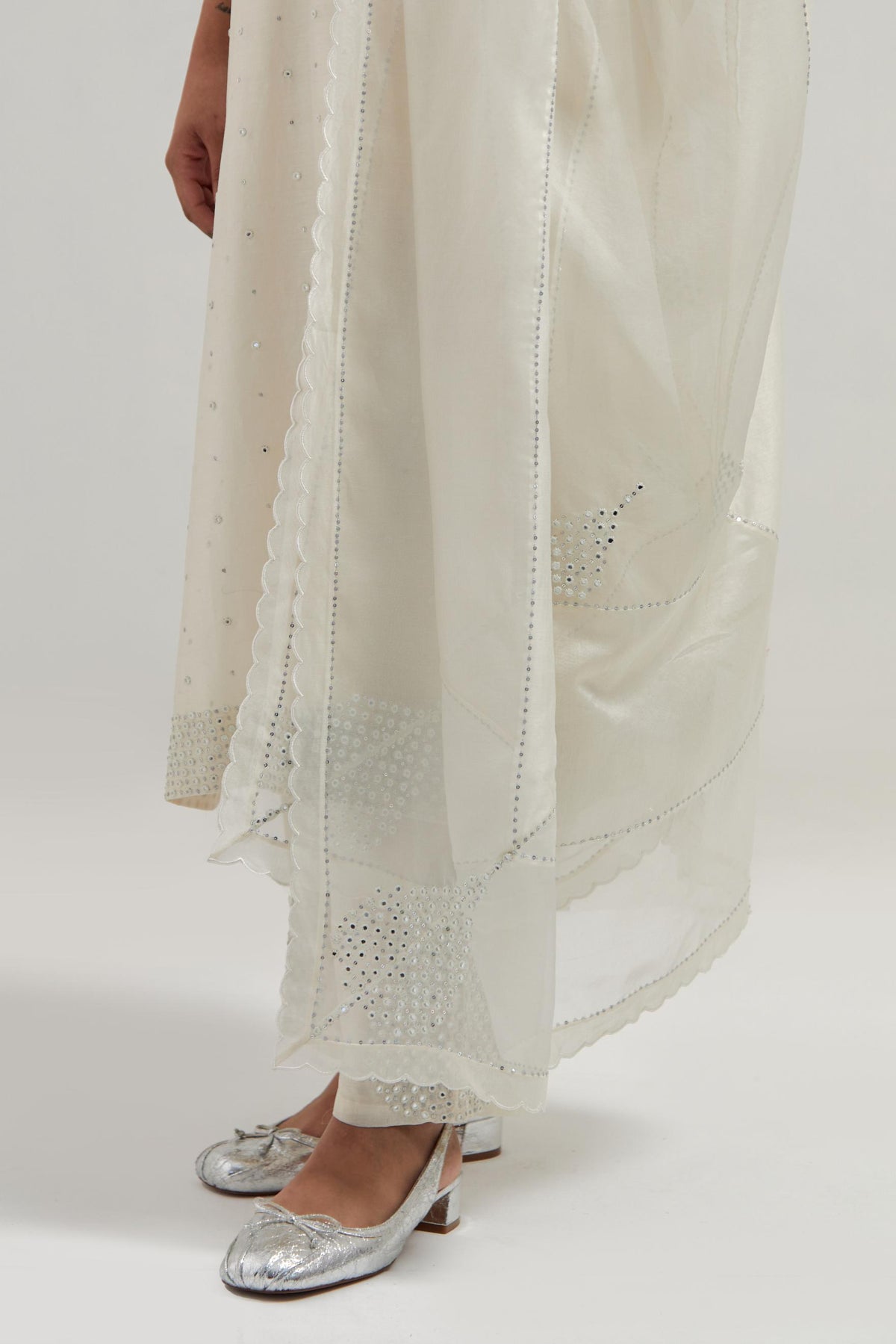 Off white silk Chanderi dupatta with silk organza at the sides, finished with delicate scalloped edges, highlighted by hand-embroidered mirror & sequins work.