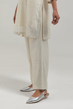 Off white silk Chanderi straight short kurta set with hand-embroidered paisley motifs with delicate mirror and sequins work at neck, hem, and sleeves, with narrow borders along the edges.