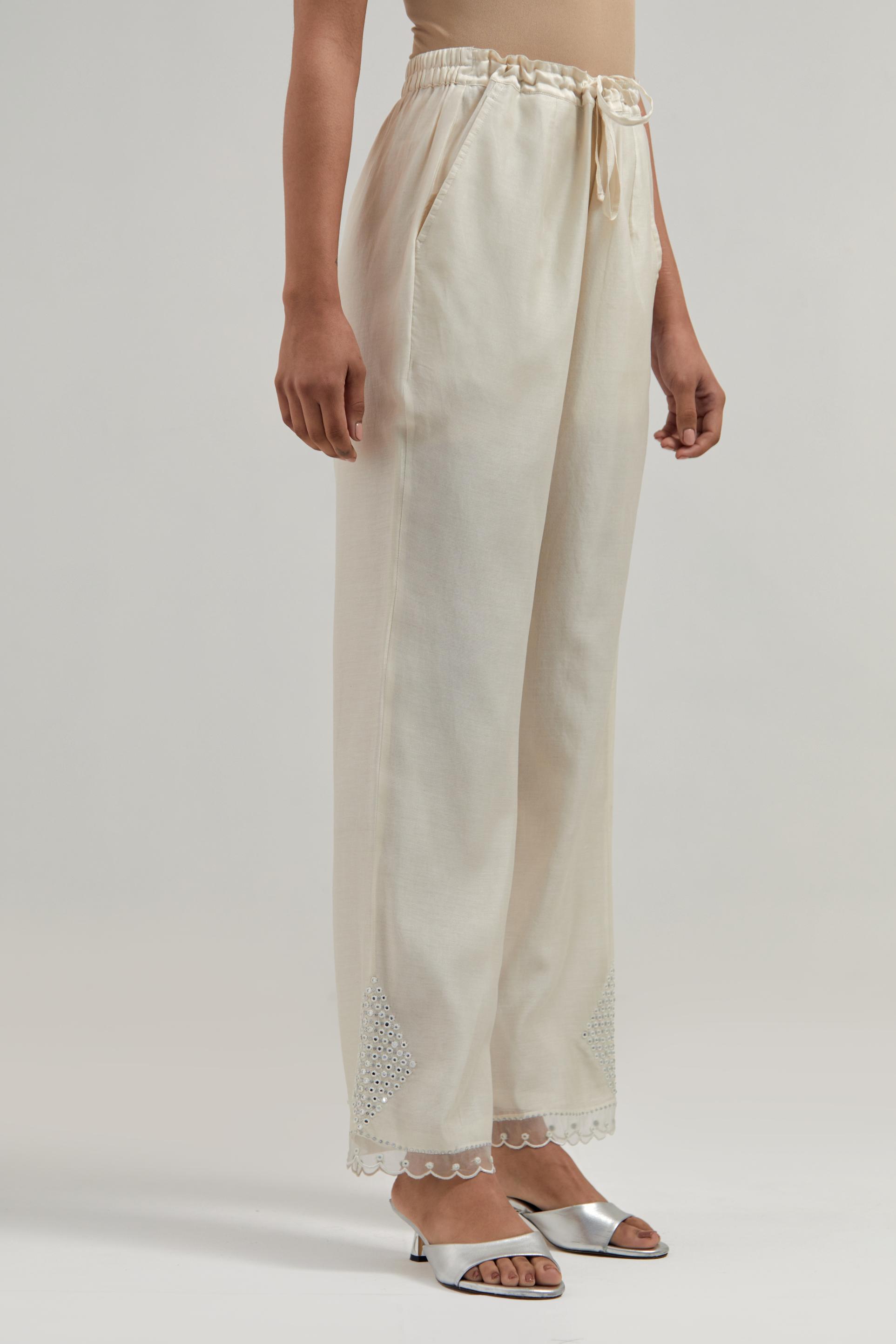 Off white silk Chanderi straight pants with narrow organza scalloped hem and hand-embroidered diamond motifs with delicate mirror & sequins work at the sides.