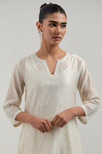 Off white silk Chanderi straight short kurta set with hand-embroidered paisley motifs with delicate mirror and sequins work at neck, hem, and sleeves, with narrow borders along the edges.