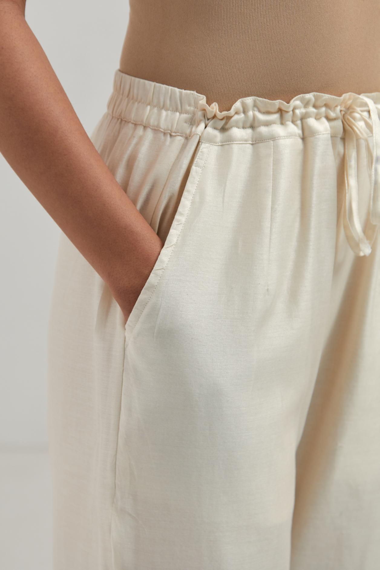 Off white Silk Chanderi pants with hand embroidered leaf motifs with delicate mirror & sequins work at hem.