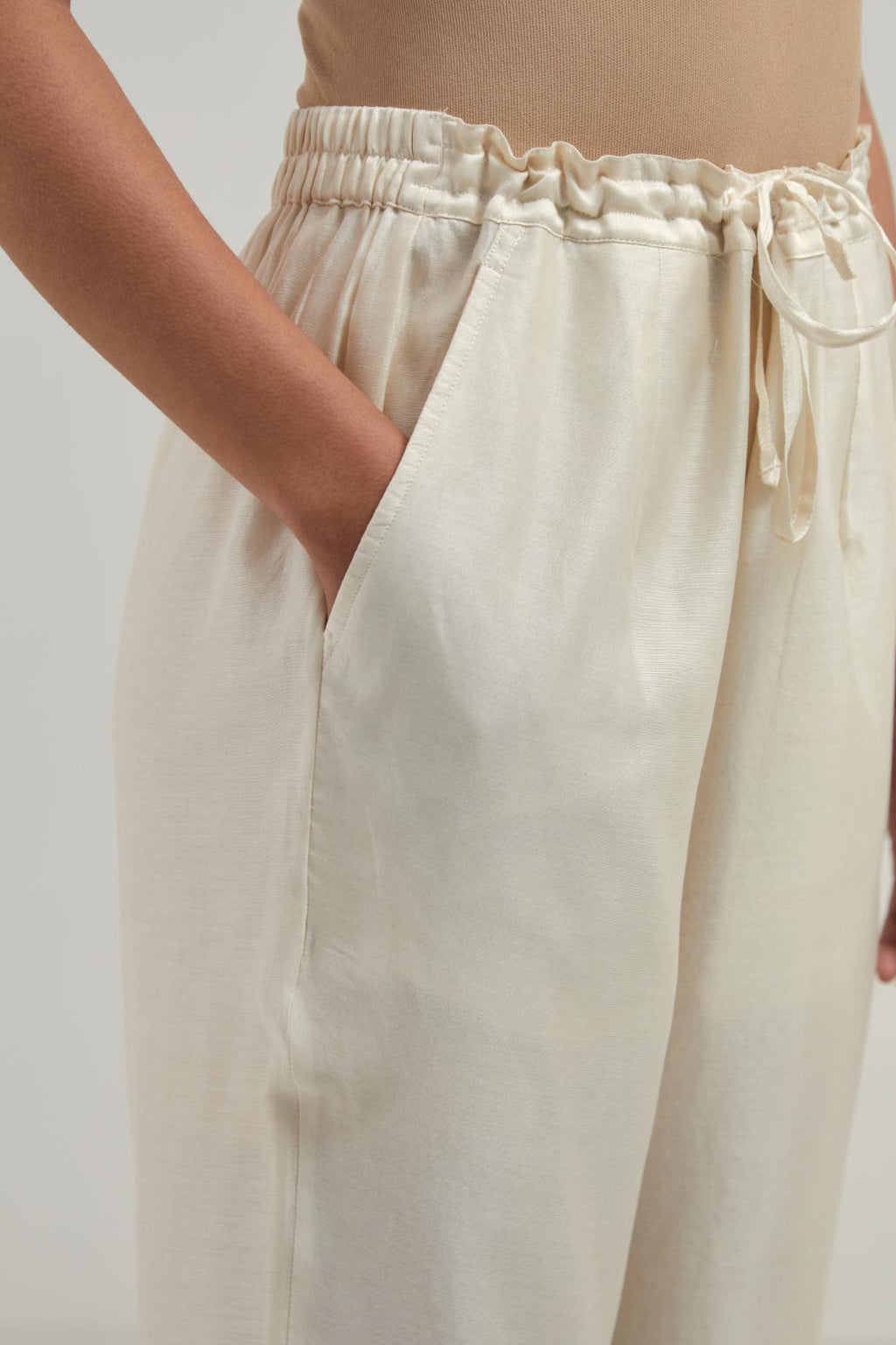 Off white silk Chanderi straight pants with narrow organza scalloped hem and hand-embroidered diamond motifs with delicate mirror & sequins work at the sides.