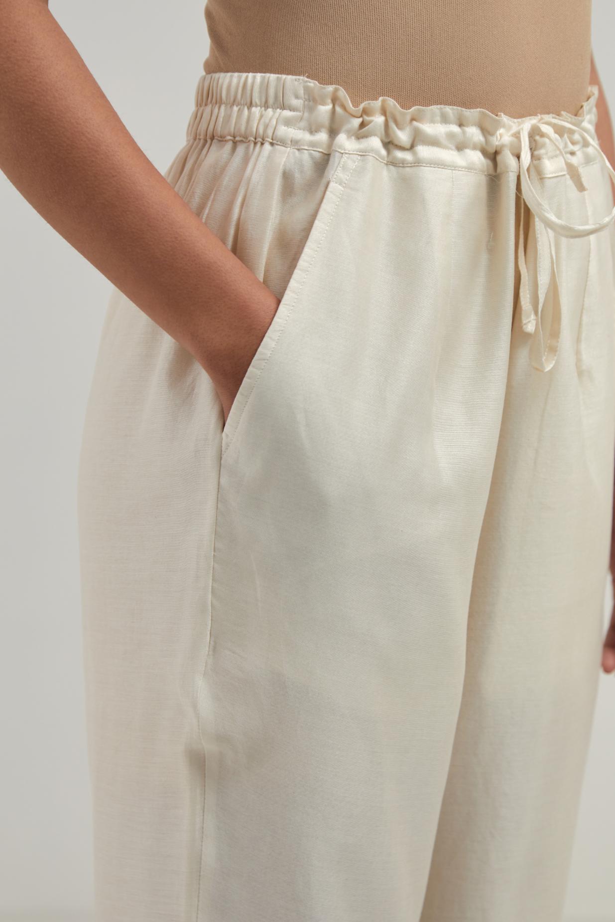 Off white silk Chanderi straight pants with narrow organza scalloped hem and hand-embroidered diamond motifs with delicate mirror & sequins work at the sides.