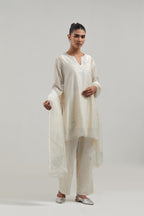 Off white silk Chanderi straight short kurta set with hand-embroidered paisley motifs with delicate mirror and sequins work at neck, hem, and sleeves, with narrow borders along the edges.