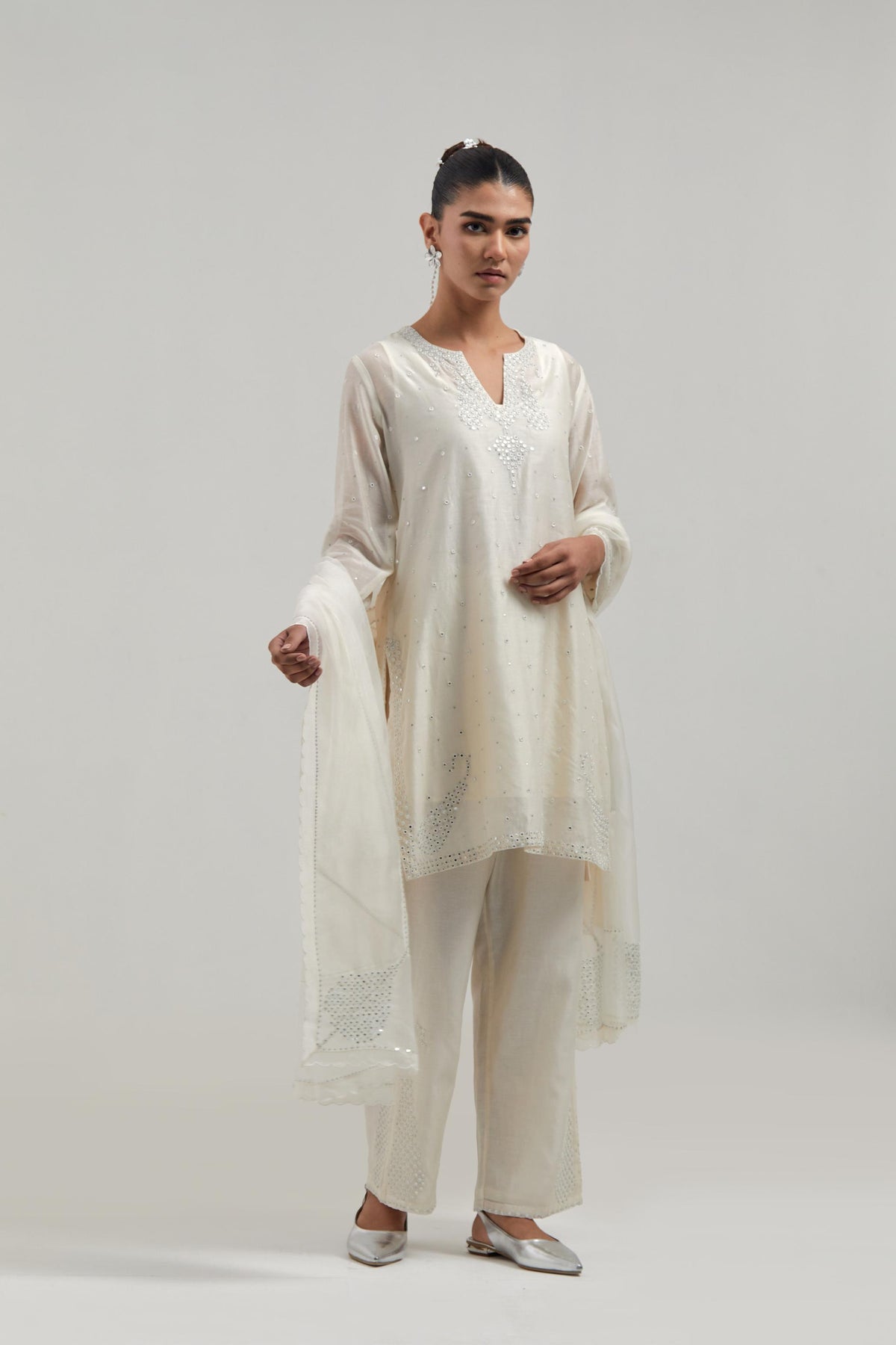 Off white silk Chanderi straight short kurta set with hand-embroidered paisley motifs with delicate mirror and sequins work at neck, hem, and sleeves, with narrow borders along the edges.