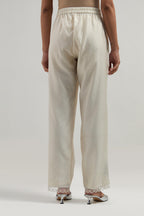 Off white silk Chanderi straight pants with narrow organza scalloped hem and hand-embroidered diamond motifs with delicate mirror & sequins work at the sides.
