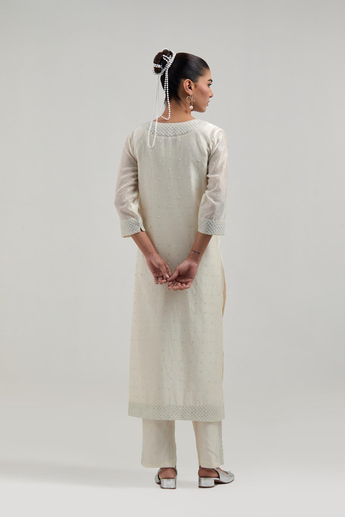 Off-white silk Chanderi straight kurta set with hand-embroidered mirror at the neck, hem and sleeves, highlighted with scattered silver sequin and mirror embellishments all-over.