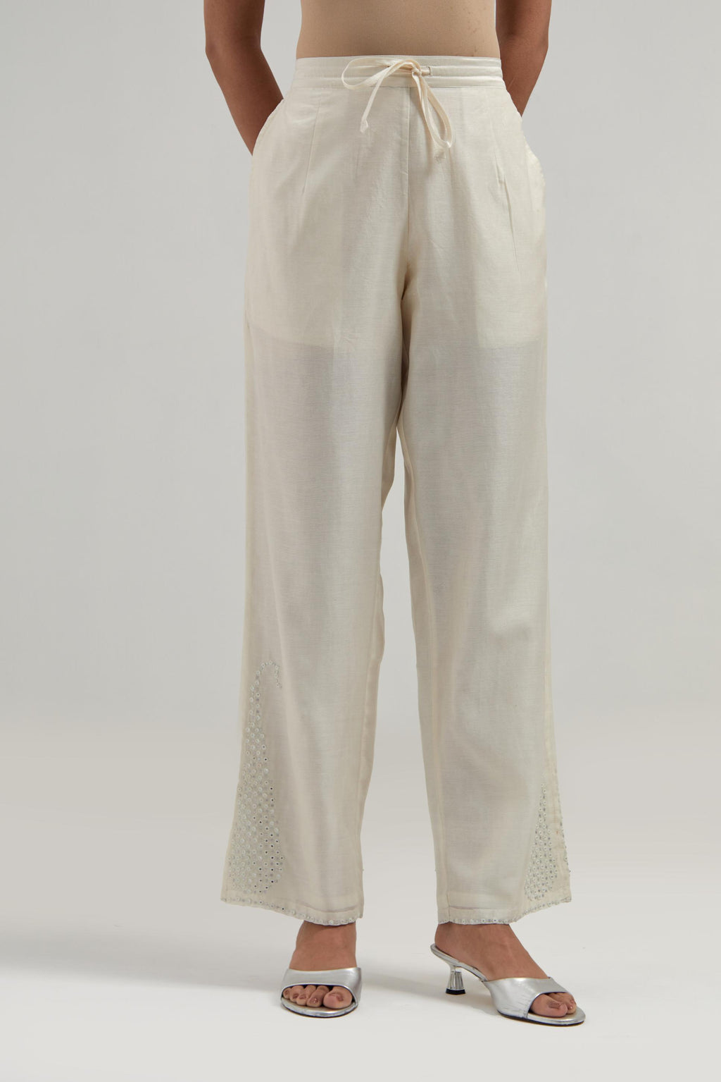 Off white silk Chanderi pants with hand-embroidered paisley motifs with delicate mirror and sequins work at the hem.