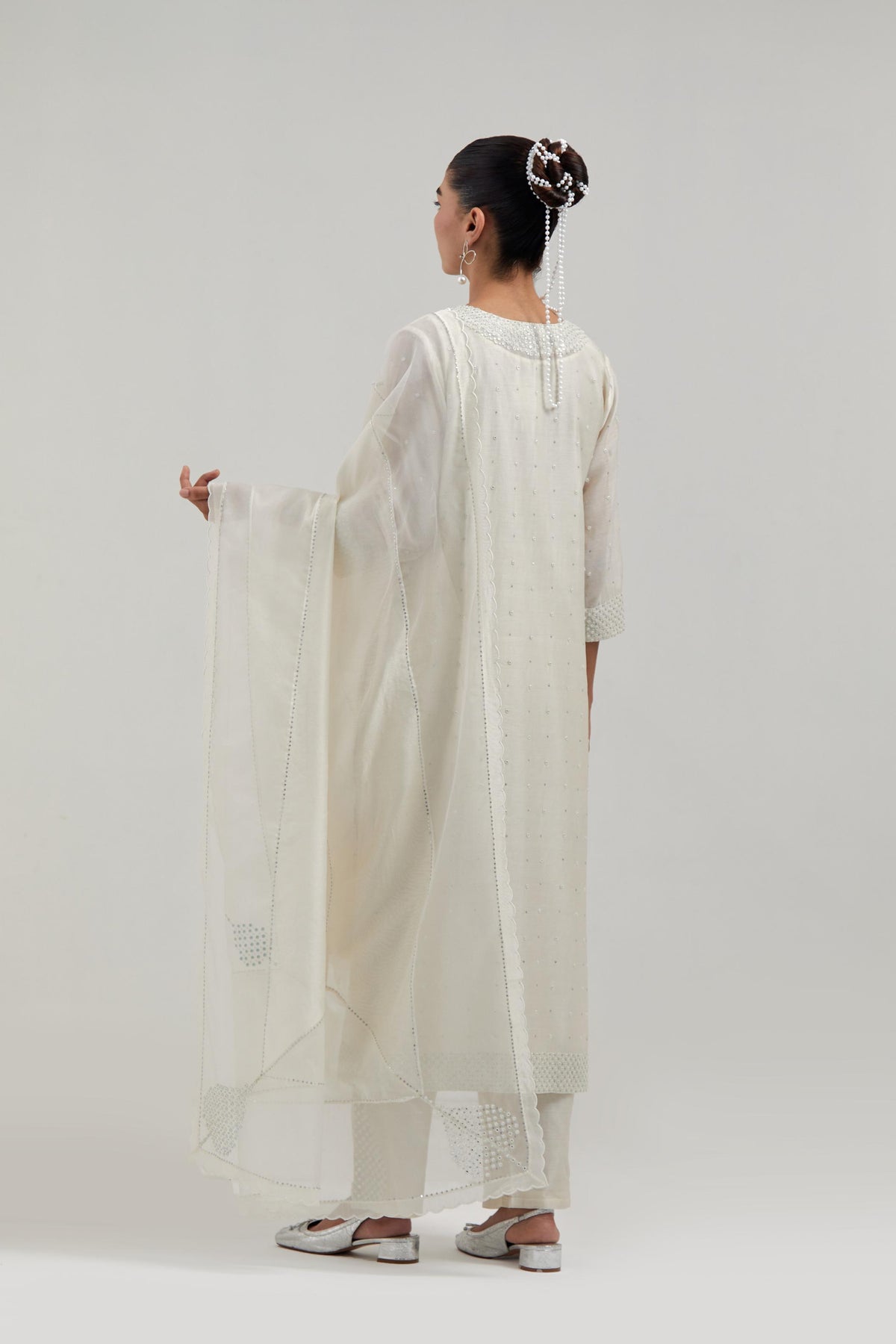 Off-white silk Chanderi straight kurta set with hand-embroidered mirror at the neck, hem and sleeves, highlighted with scattered silver sequin and mirror embellishments all-over.