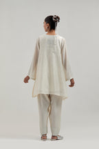 Off white silk Chanderi short A-line kurta set with hand-embroidered mirror work at the neck and bell sleeves.