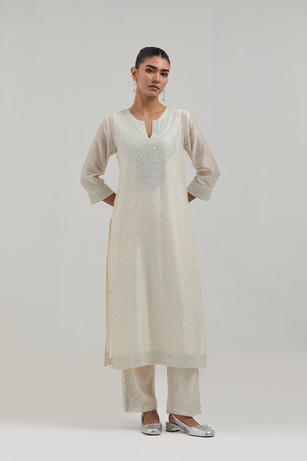 Off-white silk Chanderi straight kurta set with hand-embroidered mirror at the neck, hem and sleeves, highlighted with scattered silver sequin and mirror embellishments all-over.