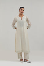 Off-white silk Chanderi straight kurta set with hand-embroidered mirror at the neck, hem and sleeves, highlighted with scattered silver sequin and mirror embellishments all-over.