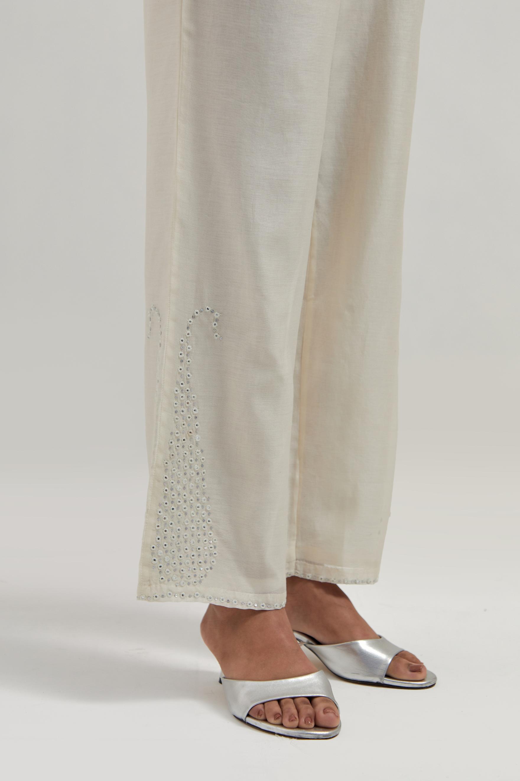Off white silk Chanderi pants with hand-embroidered paisley motifs with delicate mirror and sequins work at the hem.