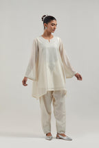 Off white silk Chanderi short A-line kurta set with hand-embroidered mirror work at the neck and bell sleeves.