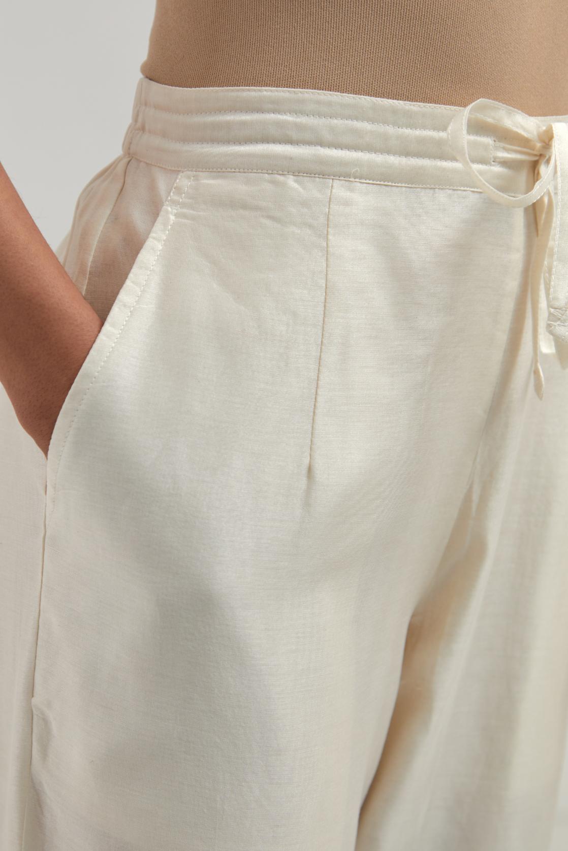 Off white silk Chanderi pants with hand-embroidered paisley motifs with delicate mirror and sequins work at the hem.
