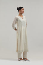 Off-white silk Chanderi straight kurta set with hand-embroidered mirror at the neck, hem and sleeves, highlighted with scattered silver sequin and mirror embellishments all-over.
