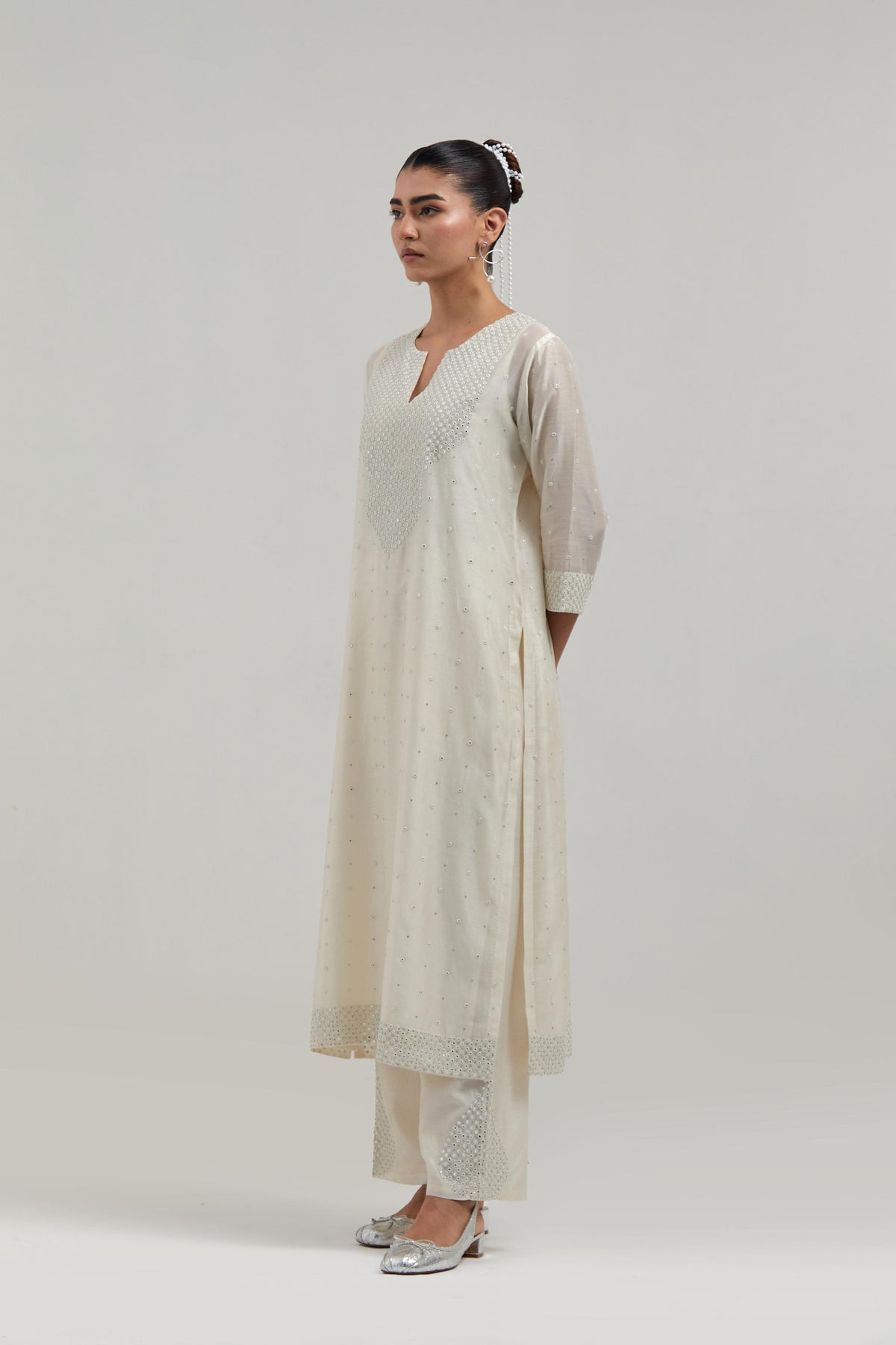 Off-white silk Chanderi straight kurta set with hand-embroidered mirror at the neck, hem and sleeves, highlighted with scattered silver sequin and mirror embellishments all-over.