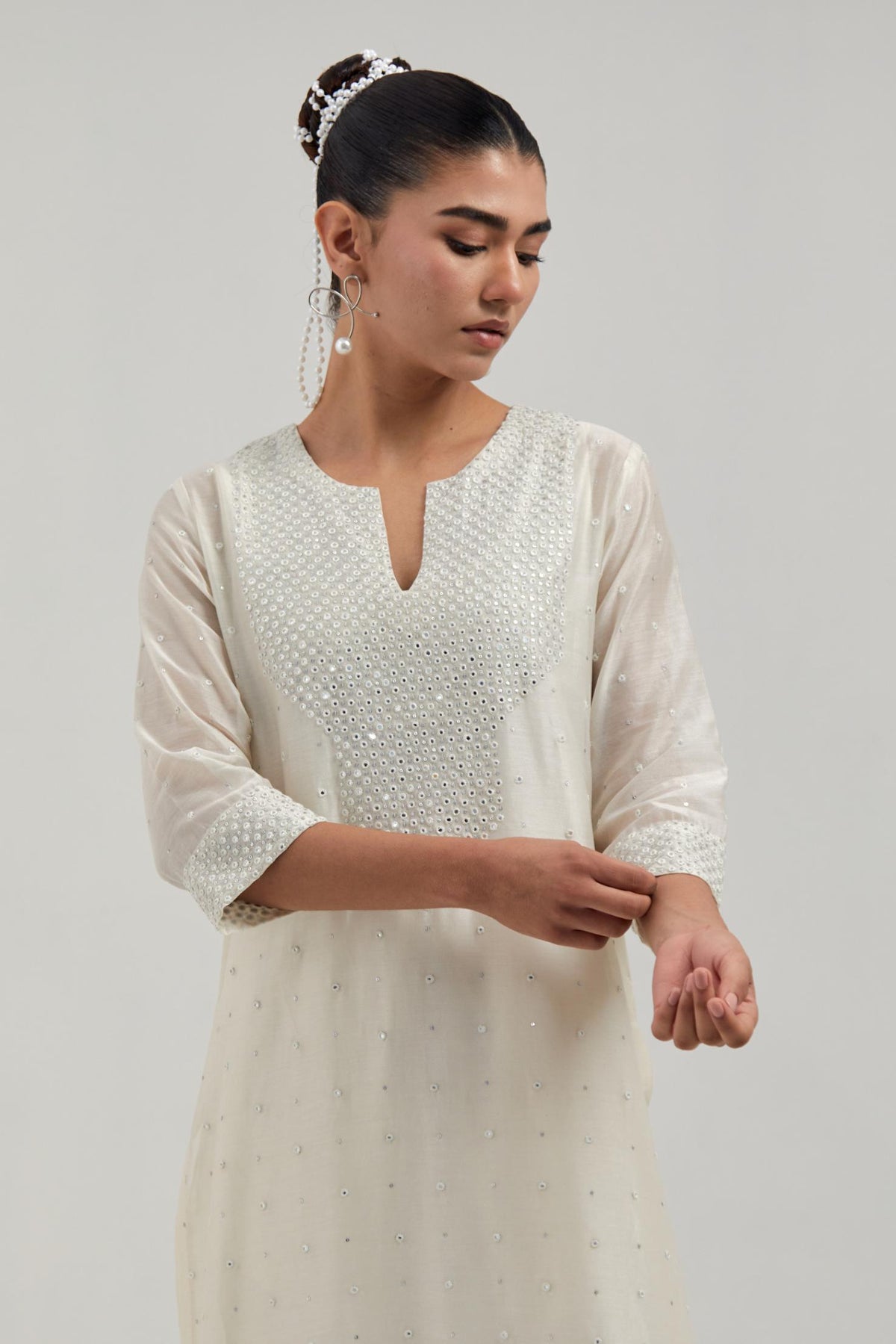 Off-white silk Chanderi straight kurta set with hand-embroidered mirror at the neck, hem and sleeves, highlighted with scattered silver sequin and mirror embellishments all-over.