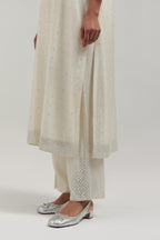 Off-white silk Chanderi straight kurta set with hand-embroidered mirror at the neck, hem and sleeves, highlighted with scattered silver sequin and mirror embellishments all-over.
