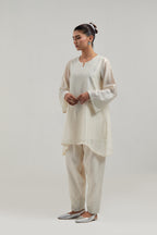 Off white silk Chanderi short A-line kurta set with hand-embroidered mirror work at the neck and bell sleeves.